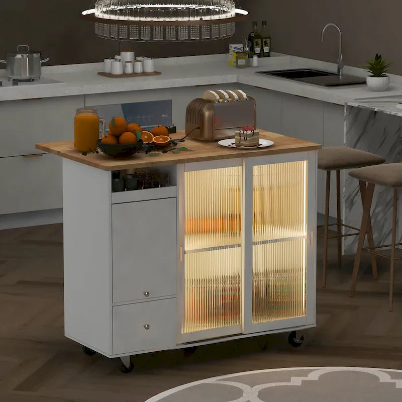 Isla de cocina con superficie abatible, luz LED, puertas de vidrio estriado, estante ajustable, dos cajones y ruedas